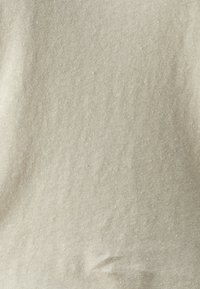 Beige katoenen stof met een gestructureerd oppervlak, met subtiele oneffenheden en een zachte, uniforme afwerking. Geschikt voor kleding of stoffering.