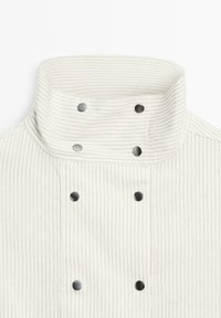 Hvid og lys grå stribet kokkeskjorte med høj krave, der har sorte trykknapper fortil til lukning og detaljer.