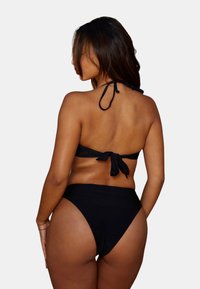Zwart bikini-set met een haltertop met een geknoopte achterkant en een high-waisted onderstuk. Het materiaal is glad met een matte afwerking.