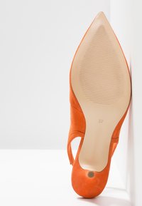 Chaussure à talon haut en daim orange à bout pointu, vue de la semelle avec la taille 37 imprimée sur la base beige.