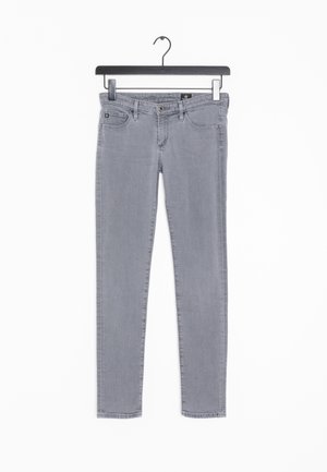 Jeans skinny grises de mezclilla, con un diseño clásico de cinco bolsillos y un sutil detalle de costura. Cuelgan de una percha negra.