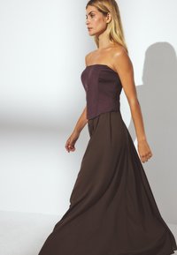 Strapless two-tone gown featuring a fitted purple bodice and flowy brown skirt, made of smooth fabric with an elegant silhouette.