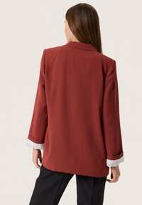 Bordový blejzr vyrobený z hladké látky, s klasickým límcem, dlouhými rukávy s ohrnutím a s upraveným střihem.