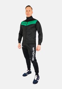 Zwarte trainingsbroek met groene accenten, ritskraag en slim-fit broek. Voorzien van het witte GIVOVA-logo op de broek en het jack. Sneakers inbegrepen.
