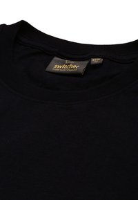 Schwarzes Baumwoll-T-Shirt mit Rundhalsausschnitt. Mit einem Etikett, das "Switcher mit Respekt hergestellt!" in goldener Schrift zeigt, Größe M, 2013.