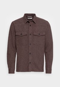 Hnědá flanelová košile s dlouhými rukávy, zapínáním na knoflíky vpředu a dvěma náprsními kapsami. Má límec a texturovanou látku.