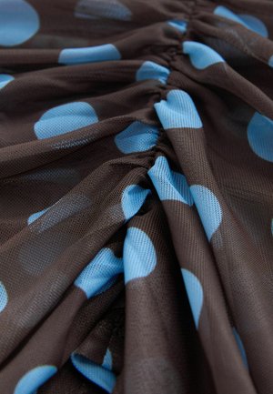 Ruda audinys su šviesiai mėlynais taškeliais, turintis surinktą tekstūrą. Medžiaga atrodo lengva ir šiek tiek permatoma.