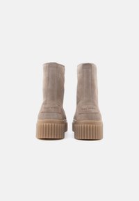 Stivaletti in suede taupe con suole a piattaforma beige rigate. Presentano cuciture laterali e il nome del marchio stampato sul tallone.