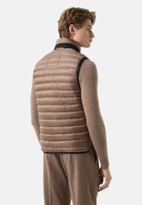 Gesteppte Weste aus hellbraunem Nylon mit hohem Kragen und ärmellosem Design. Verfügt über schwarze Akzente und ein strukturiertes, gesteppte Muster.