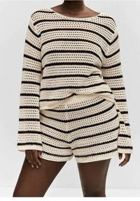 Ensemble de vêtements d'intérieur en maille comprenant un pull ample crème et un short à rayures horizontales noires, fabriqué en tissu léger et texturé.