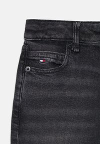 Zwarte denim jeans met een gestructureerde afwerking, voorzien van een voorzak, metalen knoop en een klein tri-kleurig logolabel op de zak.