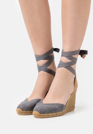 Espadrilles en toile grises avec une tige en tissu et une semelle en jute, présentant des brides de cheville croisées en ruban gris et un design de bout en V.