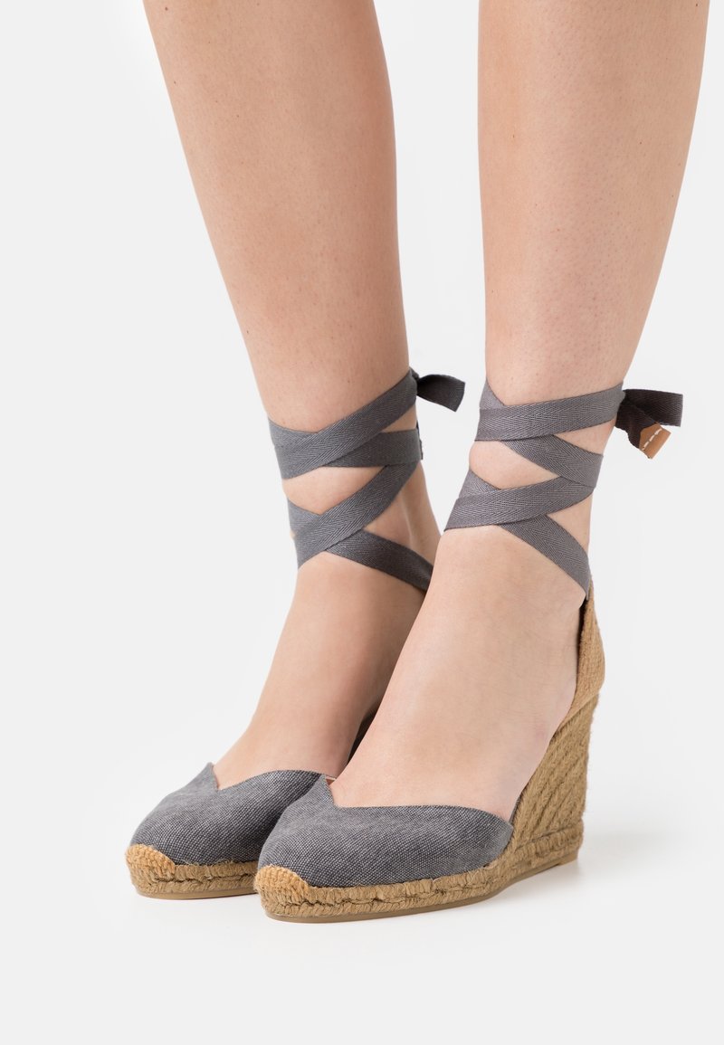 Grå kileespadriller med en overdel af stof og en sål af jute, der har krydsede grå bånd om anklen og et V-formet tådesign.