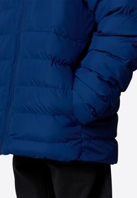 Giacca piumino blu navy con design a quilt orizzontale, chiusura con zip e tasche laterali. Texture liscia con isolamento per garantire calore.