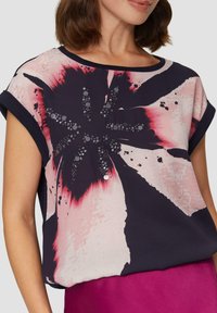 Top navy a maniche corte con un motivo floreale rosa e bianco e dettagli in paillettes. Tessuto morbido con una vestibilità rilassata e scollatura rotonda.
