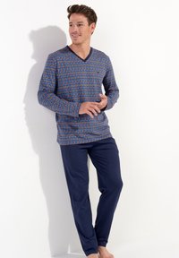 Blue patterned long-sleeve top with a V-neck and navy blue pants. The top features a vibrant geometric design in red and green hues.