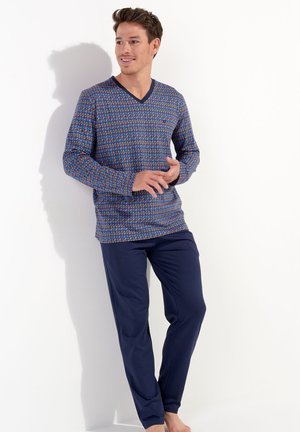 Blau gemustertes Langarmoberteil mit V-Ausschnitt und marineblauen Hose. Das Oberteil hat ein lebhaftes geometrisches Design in Rot- und Grüntönen.