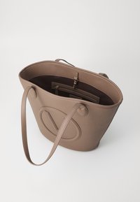 Borsa a tote in pelle marrone con texture, dotata di lunghe tracolle, ampio interno aperto e tasca con zip. Presenta un logo circolare impresso sul davanti.
