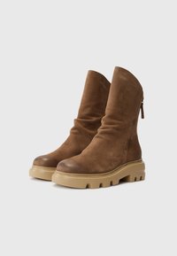 Brune lær ankle boots med et slouchy design, rund tå og tykk crepe gummisåle med notches. Sidelomme for enkel påkledning.