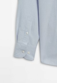 Poignet de chemise bleu clair à manches longues avec des fines rayures verticales foncées, deux boutons de poignet et un bouton sur la fente de manche.