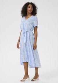 Abito midi azzurro chiaro con motivo paisley, maniche corte e una cintura a fiocco in vita. Presenta un scollo a V e un tessuto fluido.