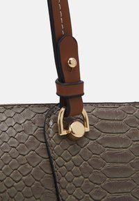 Szara torebka o teksturowanej powierzchni z nadrukiem w wzór węża, wyposażona w brązowy skórzany pasek i złote okucia. Charakterystyczne szczegóły to obszyte krawędzie i akcenty.