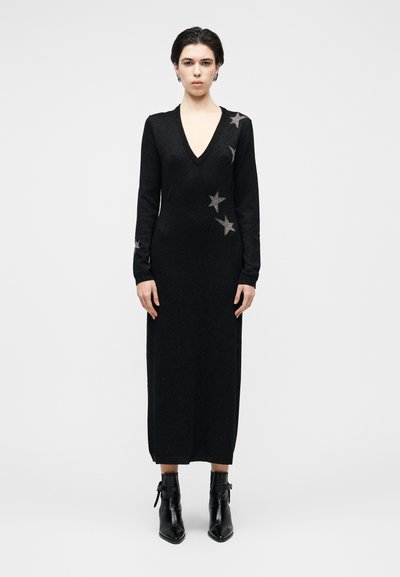 Robe en maille noire à manches longues avec un décolleté en V profond, ornée d'accents argentés en forme d'étoiles sur l'épaule gauche. Tissu texturé, silhouette ajustée.