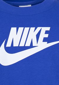 Niebieska bawełniana bluza z dużym białym logo Nike i charakterystycznym znakiem Swoosh wyraźnie eksponowanym z przodu.