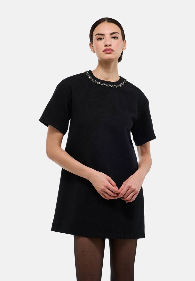 Robe noire à manches courtes avec un col rond orné d'ornements décoratifs. Le tissu semble doux avec une texture lisse.