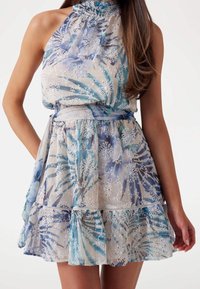 Robe à motifs floraux en tissu transparent, présentant des nuances de bleu et de blanc, un col montant et un ourlet à volants étagé avec une ceinture assortie.