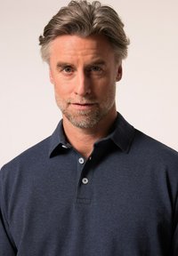 Polo en color marino fabricado con un tejido texturizado, que cuenta con un cuello, tres botones y una silueta ajustada.