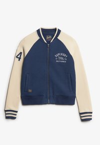 Cazadora bomber de cremallera en azul marino y crema con puños y dobladillo acanalados. Presenta la impresión "SUPERDRY" y el número "4" en la manga izquierda. Tejido suave.