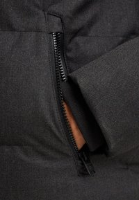 Čierna prémiová páperová bunda so zipsovým vreckom a textúrovanou tkaninou. Obsahuje pevný zips a mäkkú vnútornú podšívku.