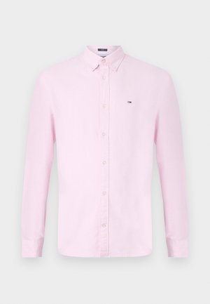 Gaiši rozā kokvilnas krekls ar garām piedurknēm un pogu aizdari, klasiskā apkakle un neliela emblēma uz krūtīm. Taisna piegriezuma, ar pogām aizdarām piedurknēm.