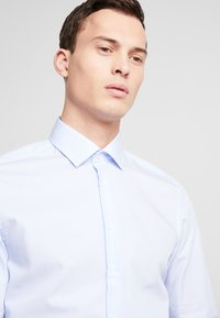 Lichtblauw gestreept overhemd, met knoopsluiting, voorzien van een klassieke kraag en een gladde textuur, met verticale strepen en een getailleerde pasvorm.