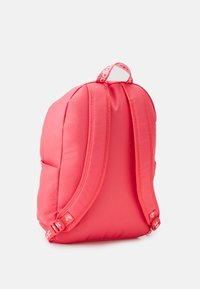 Raudona Adidas kuprinė su paminkštintais petnešomis ir logotipo kilpa, parodoma iš nugaros ant balto fono.