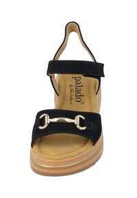 Sandalo con zeppa nera e tomaia in suede, soletta beige e una fibbia decorativa dorata. Presenta una fascia alla caviglia e una suola piattaforma.