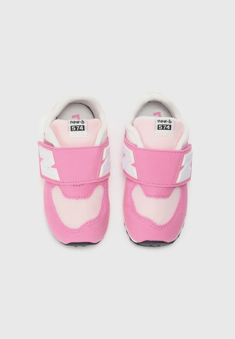 Zapatillas New Balance 574 en color rosa con parte superior de malla y ante, que cuentan con acentos del logo en blanco y correas de velcro ajustables. Suelas de goma negra.