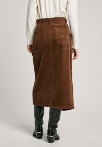 Gonna midi in corduroy marrone con taglio dritto, dotata di due tasche posteriori, texture a costine sottile e vita piatta.