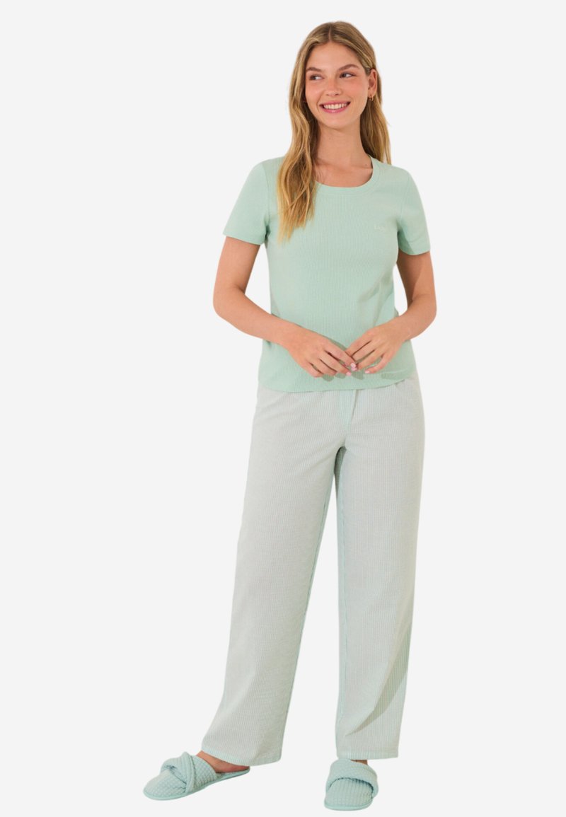 Muntgroen pyjama set met een ribbeltop met korte mouwen en lichte gestreepte broek, gecombineerd met bijpassende instappantoffels.