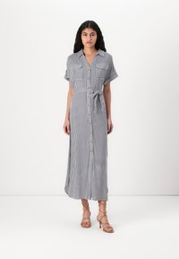 Ριγέ, πουκαμίσα midi φόρεμα σε ναυτικό μπλε και λευκό, με κοντά μανίκια, δύο τσέπες στο στήθος και ζωνάκι, φτιαγμένο από ελαφρύ ύφασμα.