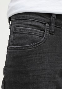 Svarta denimjeans med en klassisk femficksdesign, en smal midja och subtil sömnad längs fickorna och sömmarna.