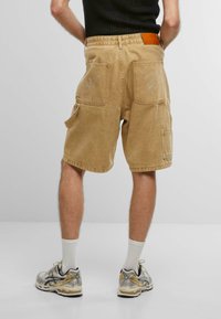 Bermudas tipo cargo en color caqui con múltiples bolsillos, que presentan letras bordadas en los bolsillos traseros. Tela de algodón, corte relajado y dobladillo enrollado.