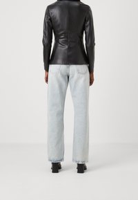 Černá kožená bunda s přiléhavým střihem a dlouhými rukávy, doplněná světle modrými vysokými širokými džíny a černými koženými botami na vysokém podpatku.