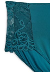 Turkusowy strój kąpielowy z misternymi koronkowymi detalami po bokach, gładką teksturą i miękkim wykończeniem. Koronka ma swobodny, wzorzysty design.