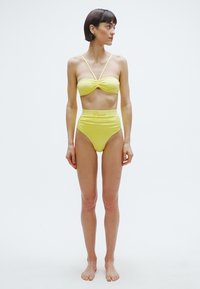 Dzeltena bikini komplekts ar plānām lencēm, kam ir savilkts bandeau topiņš un augsta vidukļa apakšdaļa. Gluda, spīdīga tekstūra ar logotipa detaļu.