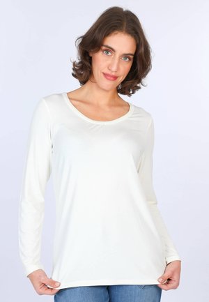 Langärmliges, weißes Hemd mit Rundhalsausschnitt, glatter Textur und sanften Raffungen vorne, kombiniert mit blauen Jeans.