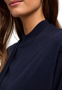 Granatowy sweter dzianinowy z wysokim kołnierzem, charakteryzujący się teksturowanym wykończeniem i gładką tkaniną, która blisko przylega do ciała.