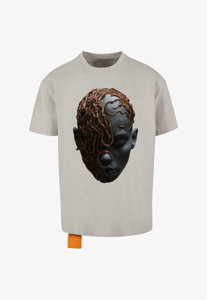 Gai pelēkais t-krekls ar krāsainu grafiku, kurā attēlota seja ar tumšu ādu un detalizēti brūni čūskveidīgi motīvi, kas sedz vienu pusi.