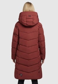 Giacca a vento rossa con motivo a zigzag, ampio cappuccio e tasche con zip. Presenta un logo sul lato sinistro inferiore e una finitura liscia e texturizzata.